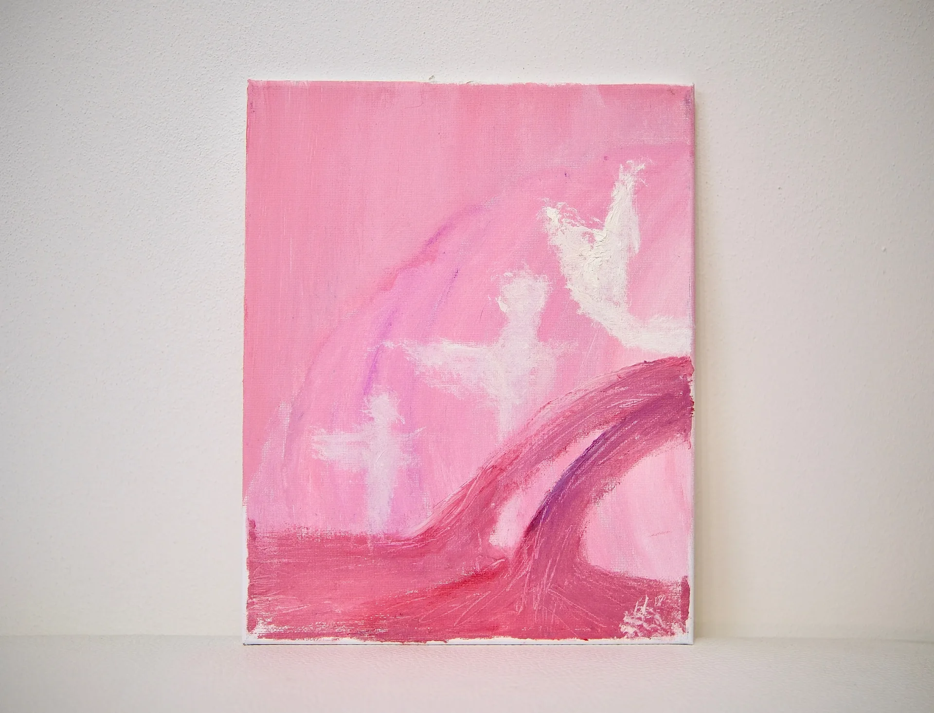 The unframed canvas propped against a white wall, its pink field and rising white figures seen straight on.