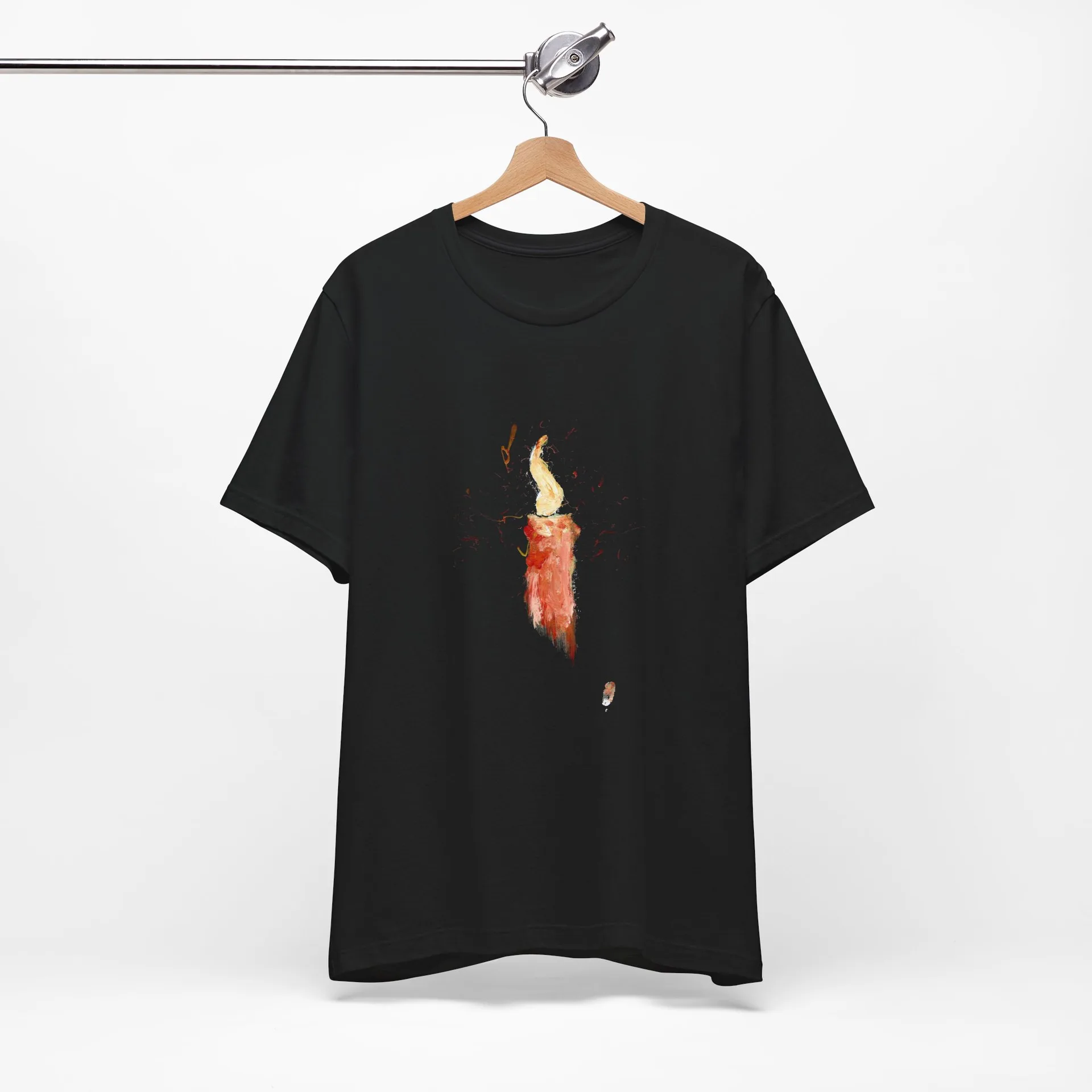 The black t-shirt on a wooden hanger suspended from a metal rail, the painted candle centred on the chest.