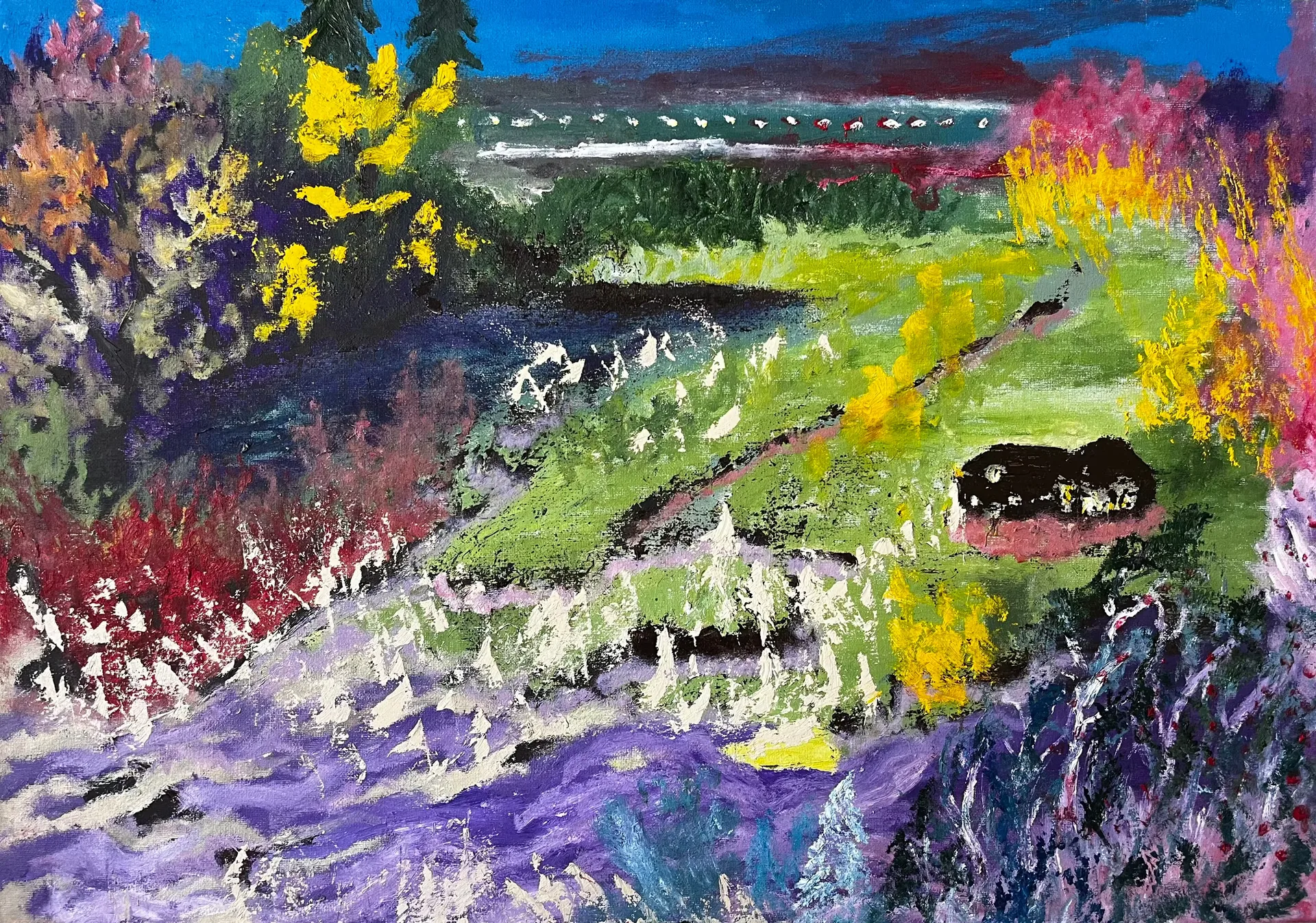 A valley in bloom: a bright green meadow crossed by dark paths falls away from a treeline, banked on both sides by scrub flowering in yellow, orange, crimson and magenta, with a broad lavender slope flecked with cream across the foreground. A small black hut sits on the right-hand slope, and a band of teal water runs under the blue sky behind.